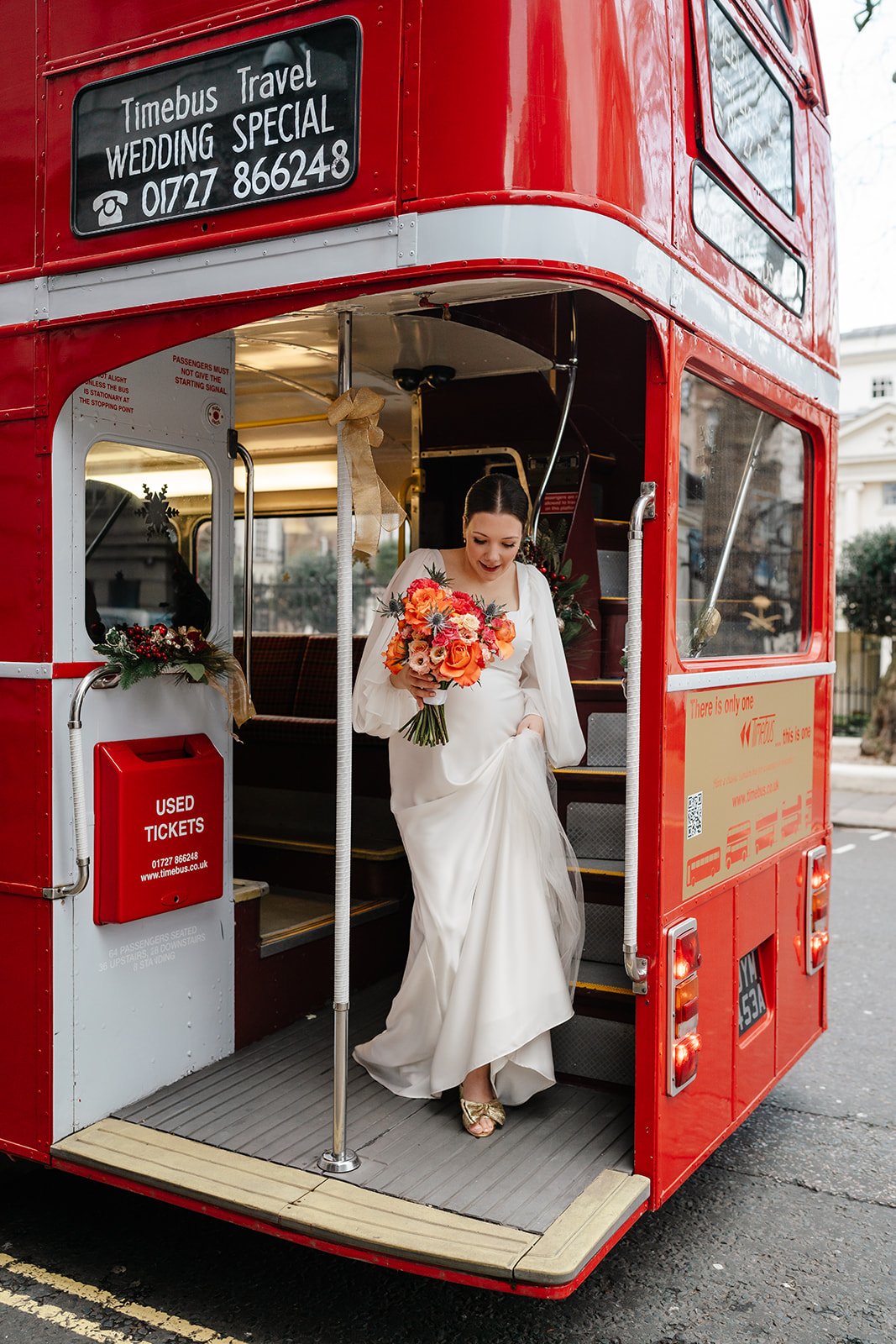 bride stepping off London red bus during Mayfair Wedding