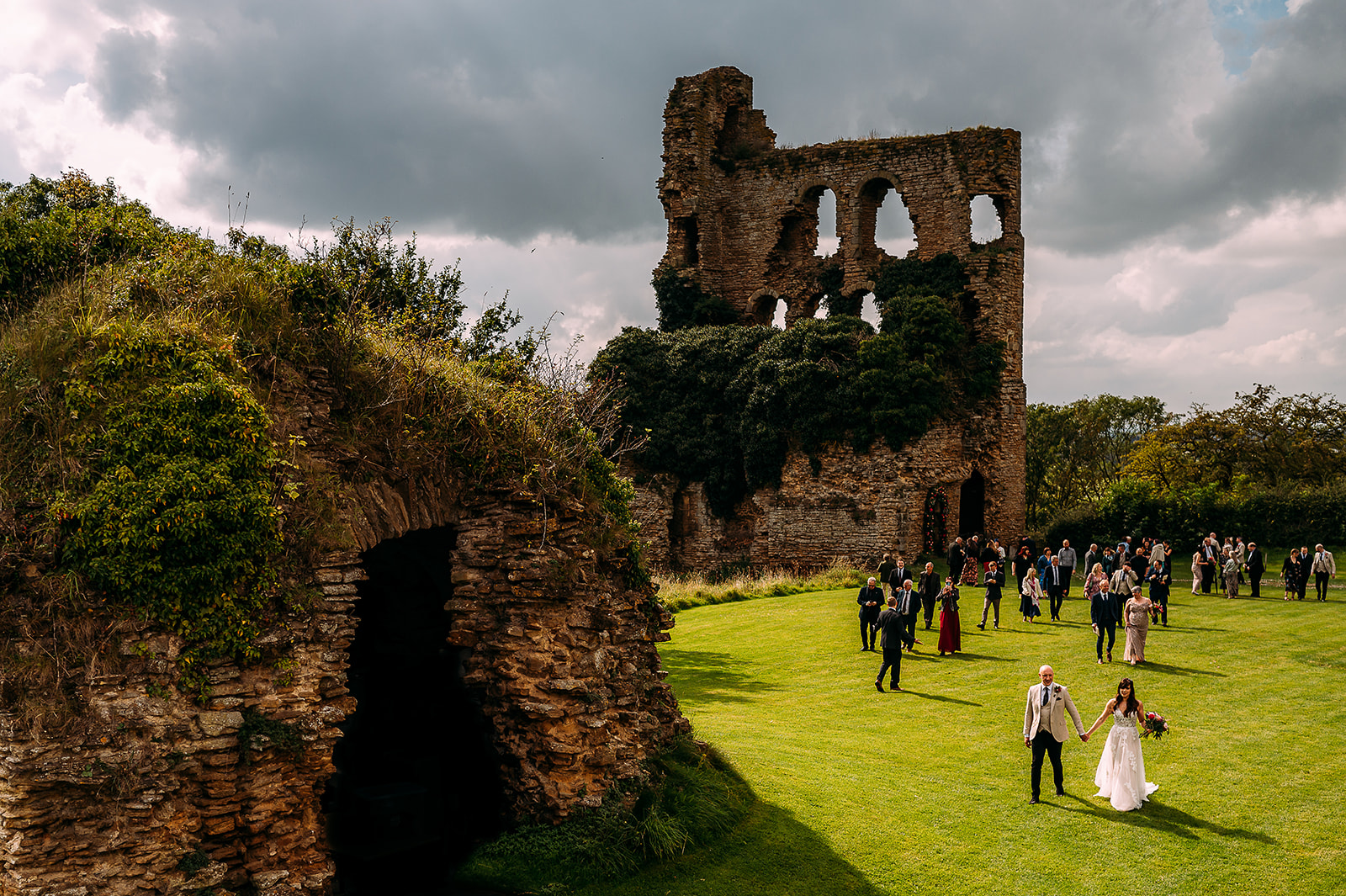 Couple and their guests walking out of their wedding ceremony at old castle ruins.