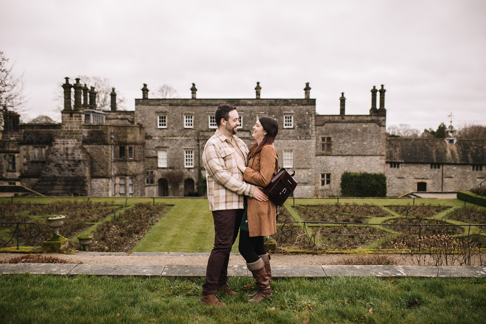 A couple cuddle in front of Tissington Hall