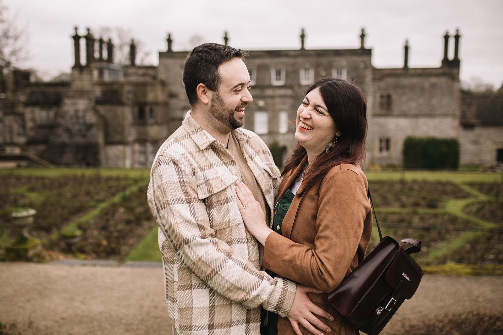 A couple laugh in front of Tissington Hall 