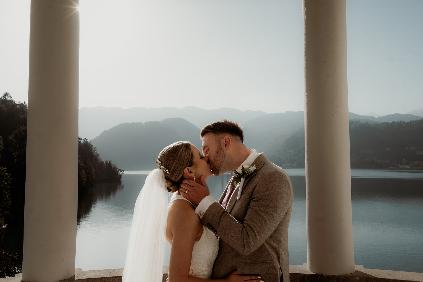 Bride and Groom share a kiss with Church on the Island in the back ground on Lake Bled Slovenia