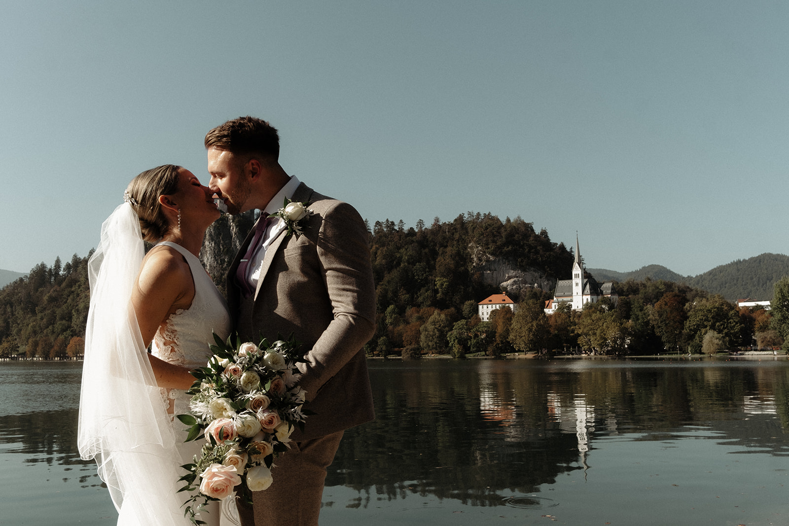 Bride and Groom kiss with Lake Bled in the background