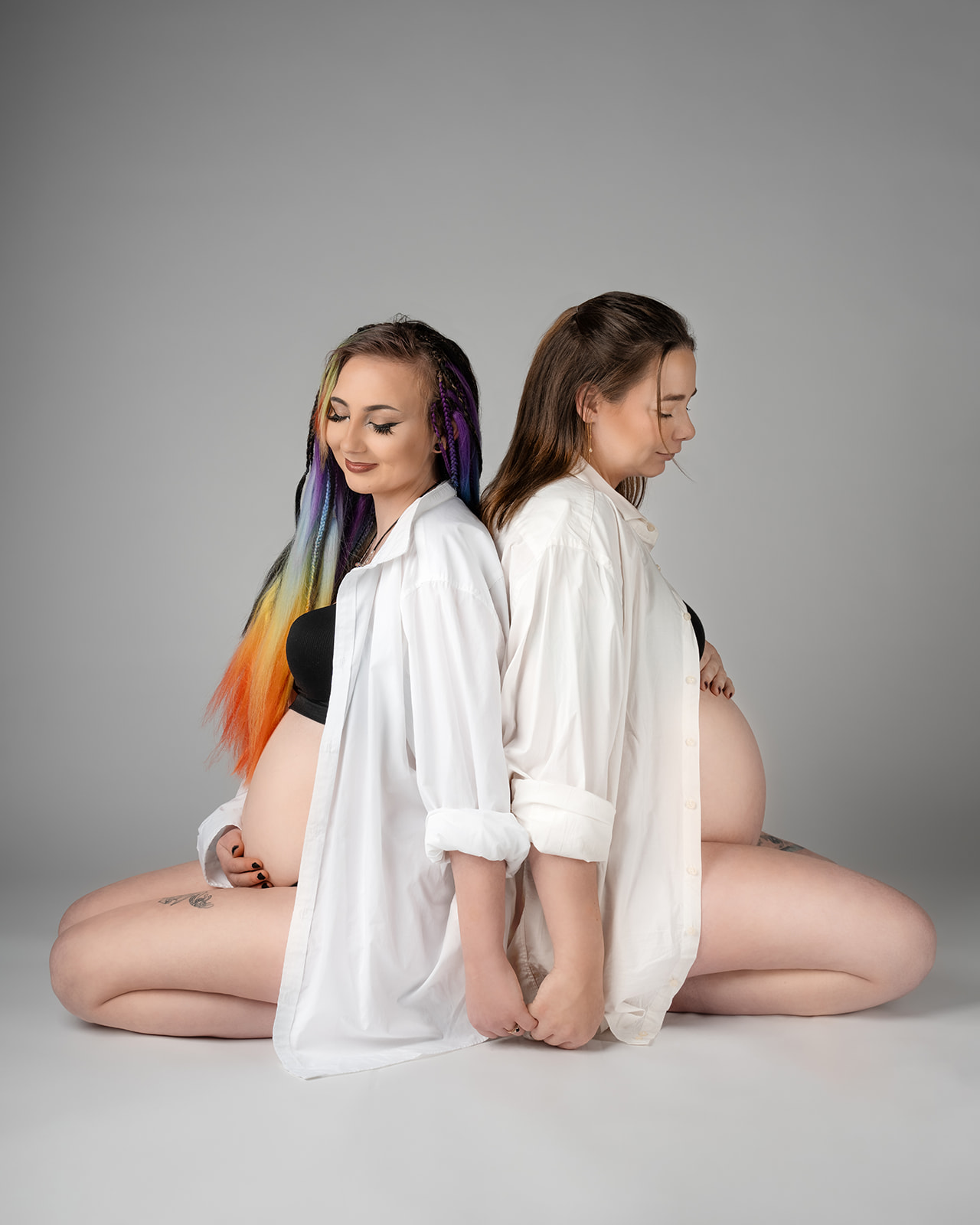 søstre der sidder på gulv gravide på samme tid