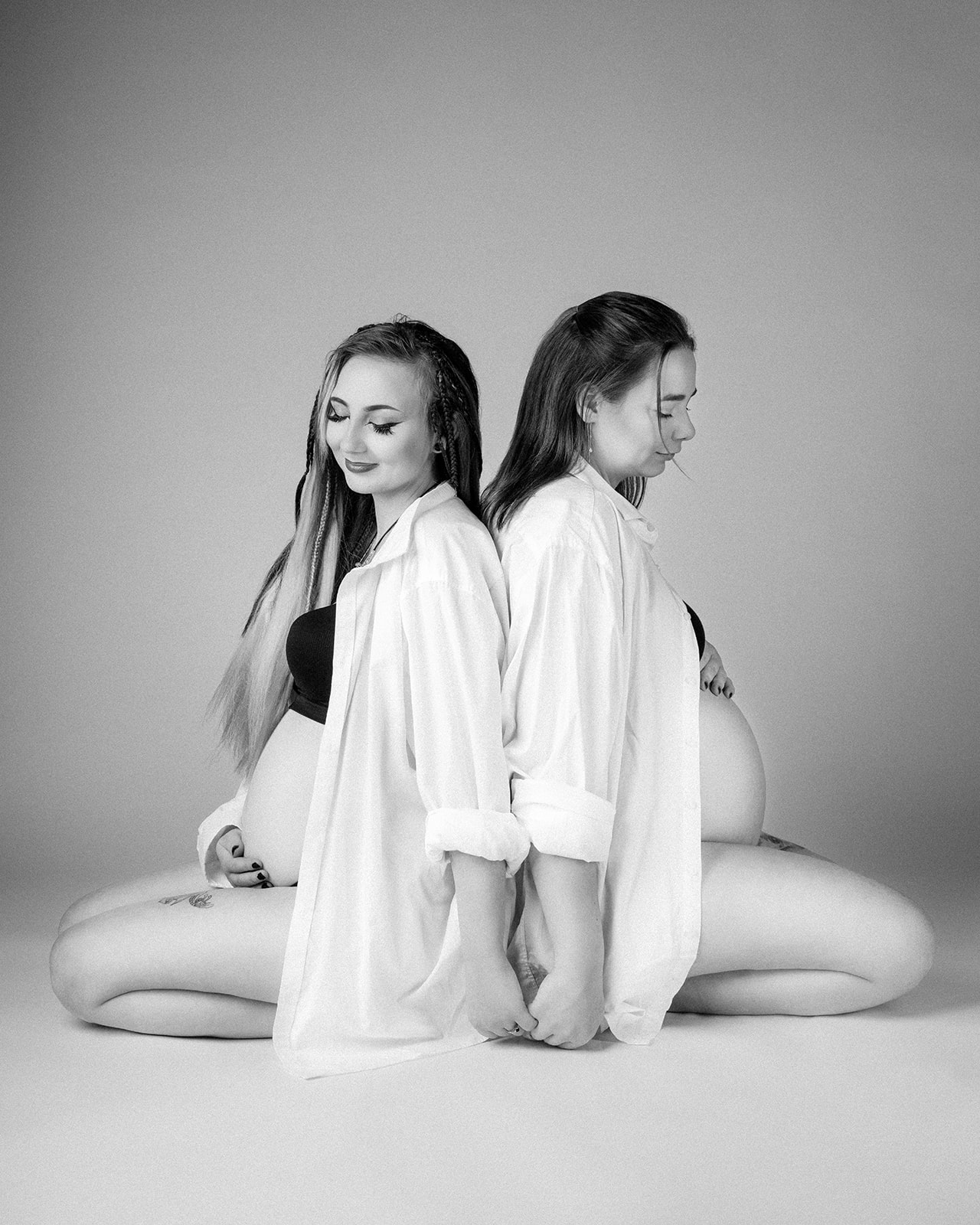 søstre der sidder på gulv gravide på samme tid i sort/hvid