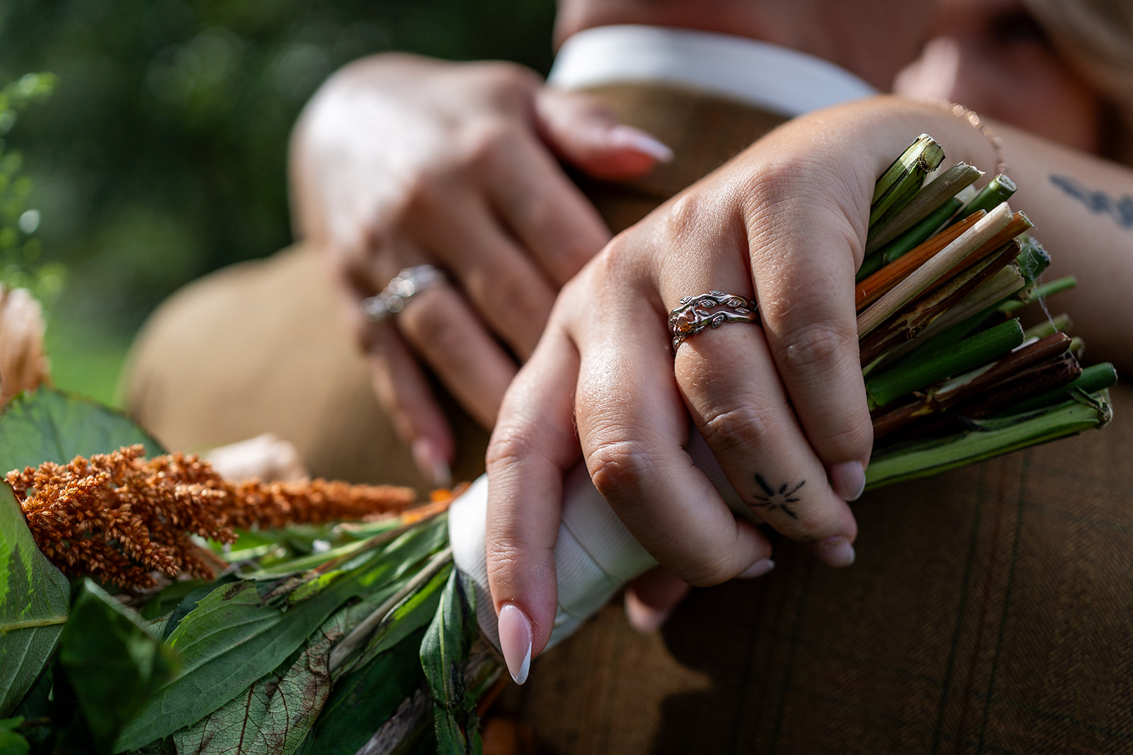 Close up shot of hand holding flowers with wedding ring visible