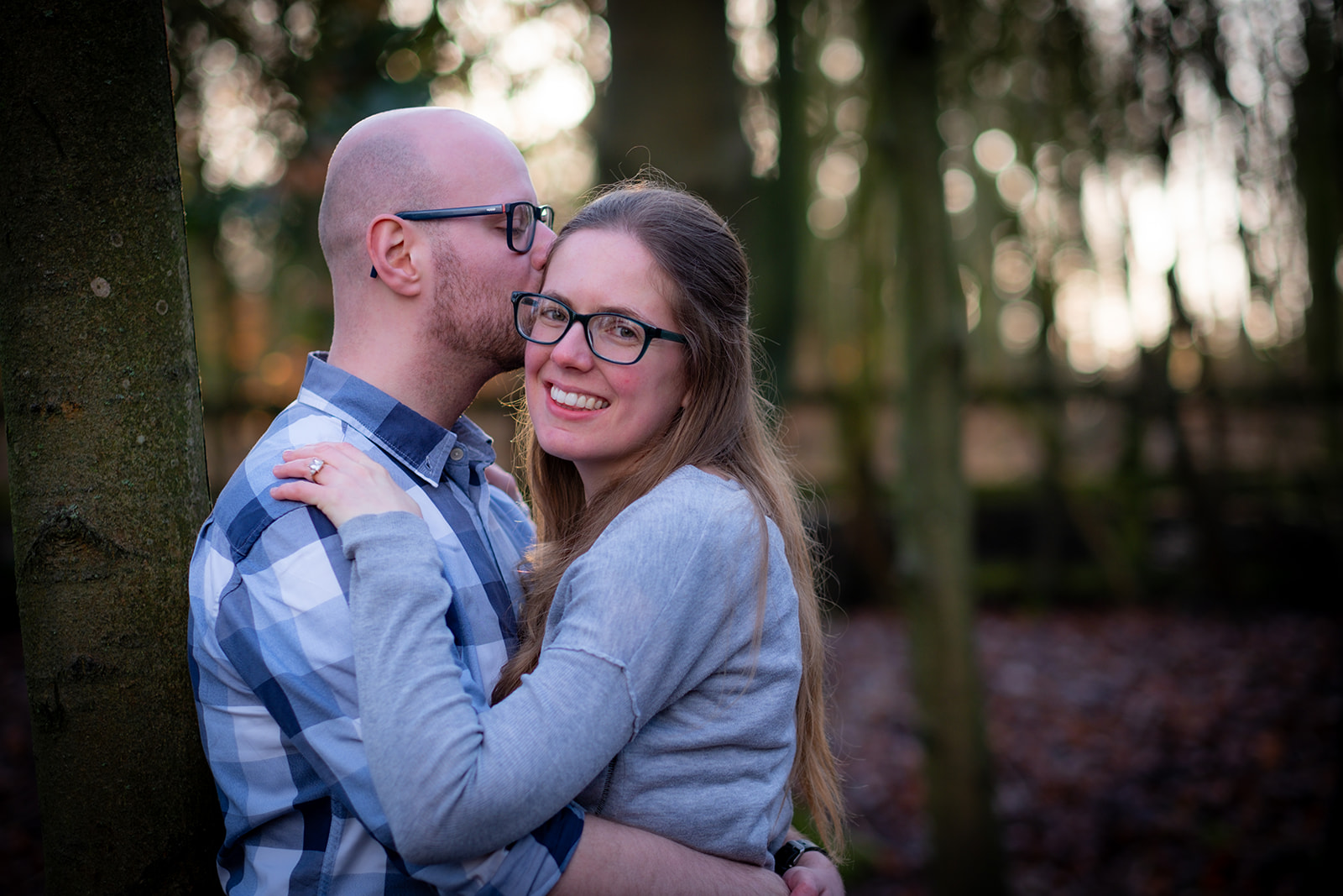 A couple embrace in the woods in their engagement shoot