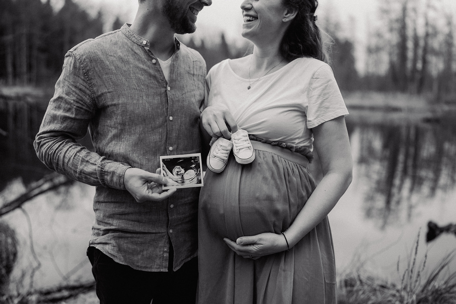 Detailfoto von Ultraschallbild Baby vor dem schwangeren Bauch mit Babyschuhen