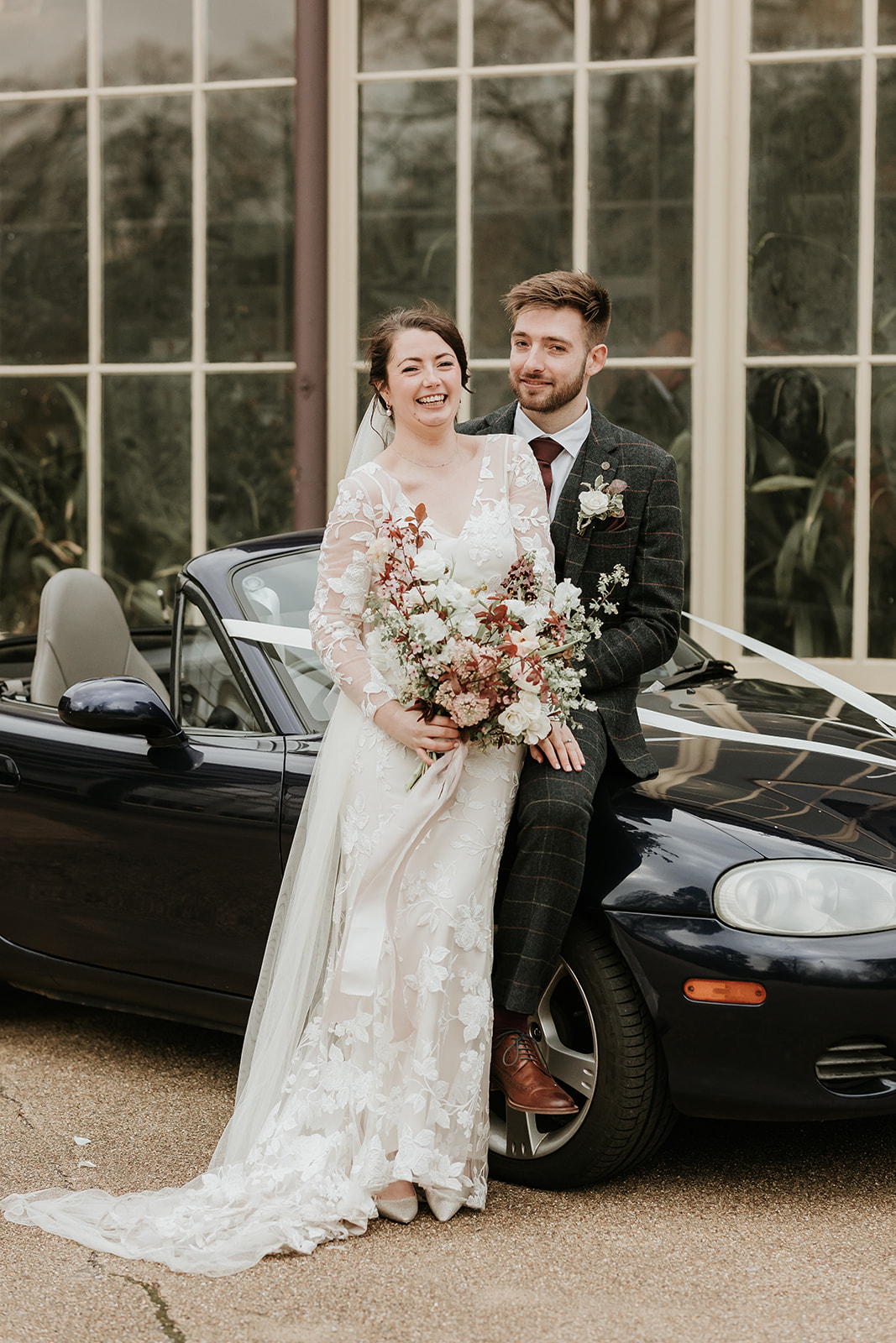 Couples portrait outside the Pavilion gardens with a classic car, lace dress and stylish suit.