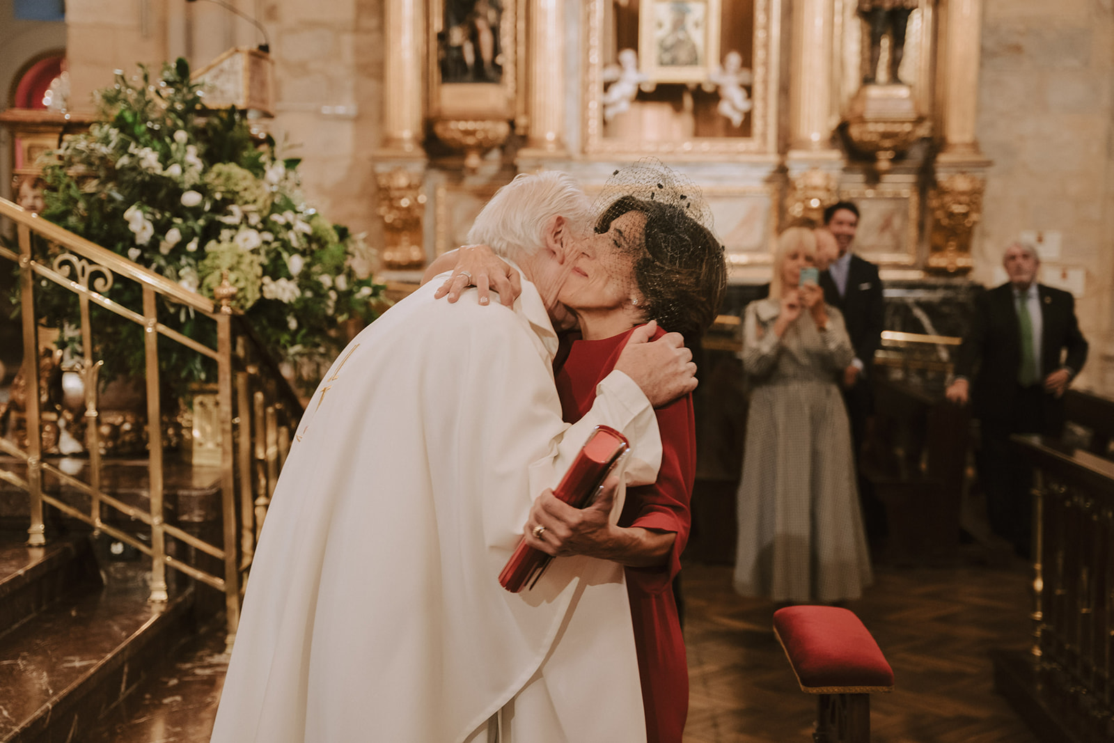 Madre de la novia abrazando al cura en la iglesia